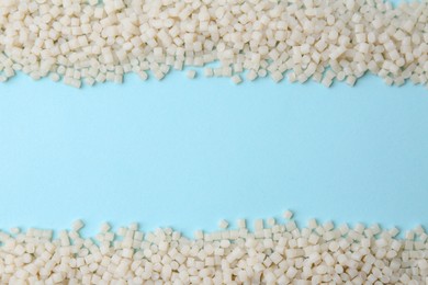 Photo of Pile of plastic granules on light blue background, top view. Space for text