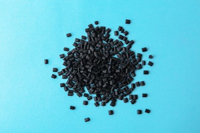 Photo of Pile of black plastic granules on light blue background, top view