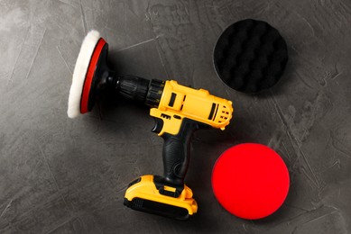 Photo of Electric screwdriver and polish pads on grey table, flat lay