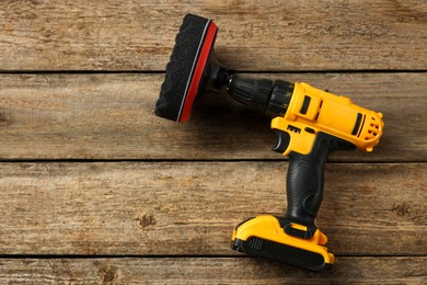 Photo of Electric screwdriver with polish pad on wooden table, top view. Space for text