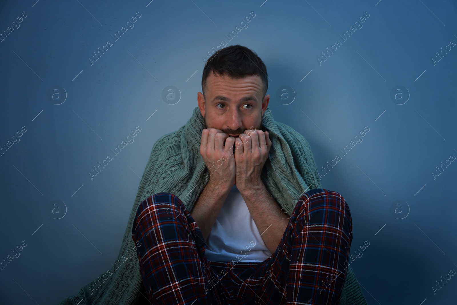 Photo of Fear of darkness. Scared man with blanket on light grey background