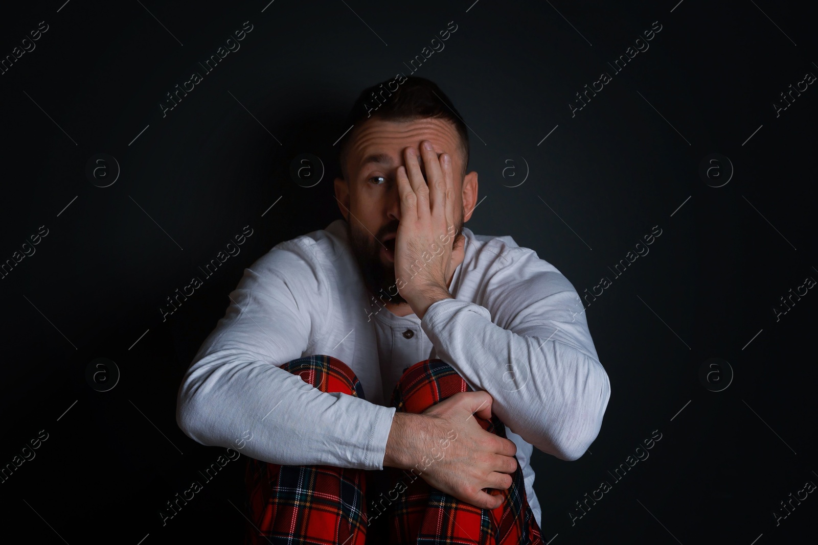 Photo of Fear of darkness. Scared man on black background