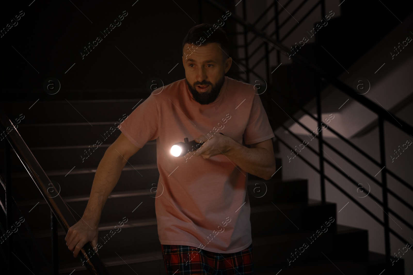 Photo of Fear of darkness. Scared man with flashlight indoors at night