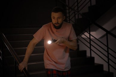 Photo of Fear of darkness. Scared man with flashlight indoors at night