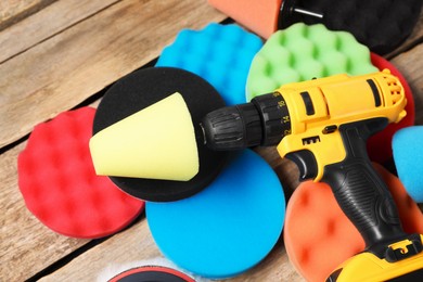 Photo of Electric screwdriver with different polish pads on wooden background, closeup