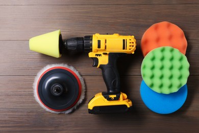 Photo of Electric screwdriver with different polish pads on wooden background, flat lay