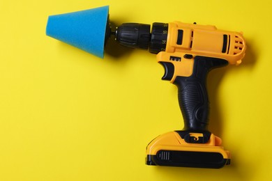 Photo of Electric screwdriver with polish pad on yellow background, top view. Space for text