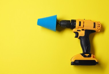 Photo of Electric screwdriver with polish pad on yellow background, top view