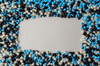 Photo of Frame of colorful plastic granules on grey background, top view. Space for text