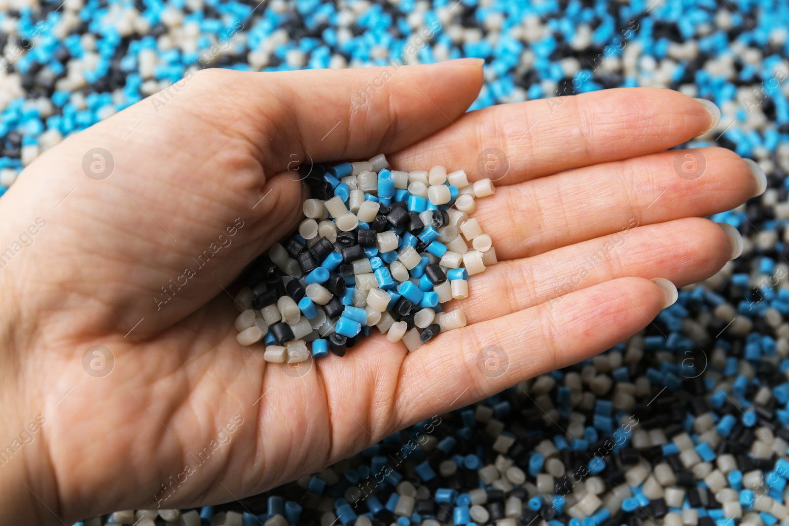 Photo of Woman with colorful plastic granules on blurred background, closeup