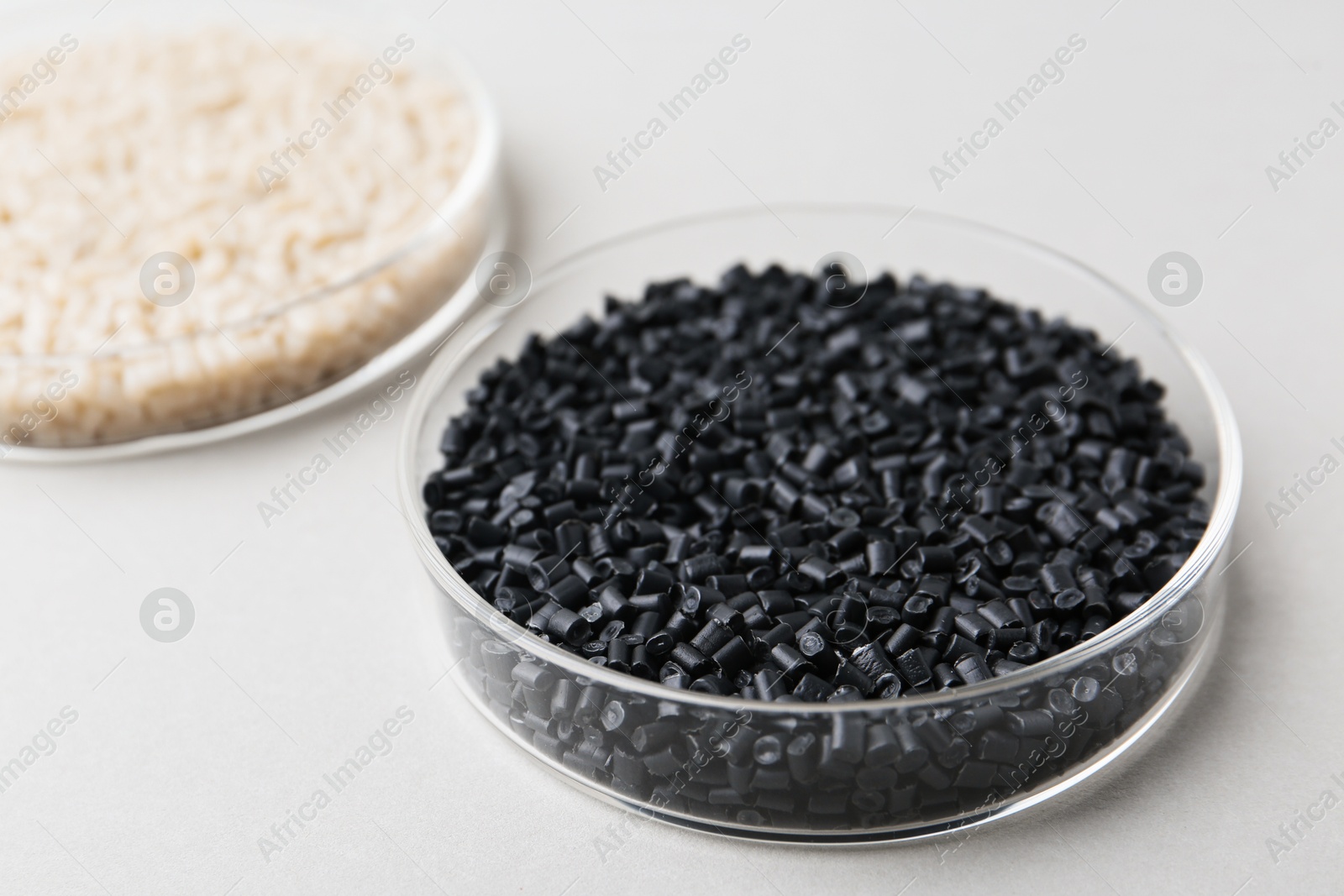 Photo of Colorful plastic granules in petri dishes on gray background, closeup