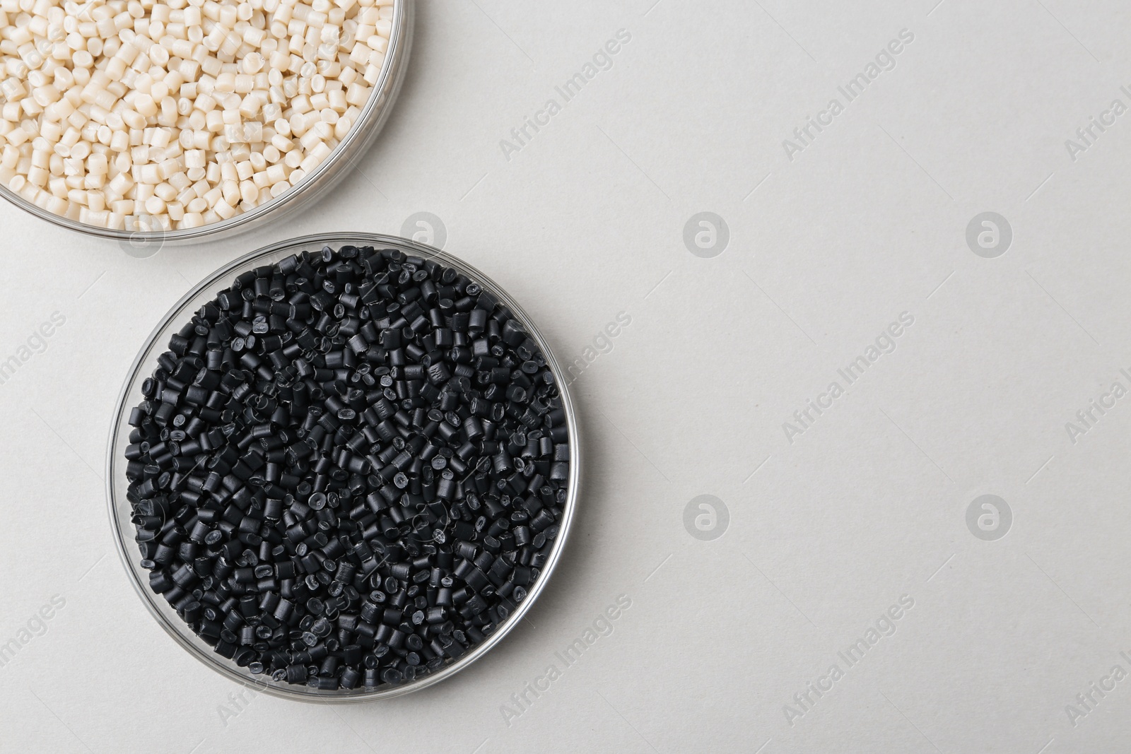 Photo of Colorful plastic granules in petri dishes on gray background, flat lay. Space for text