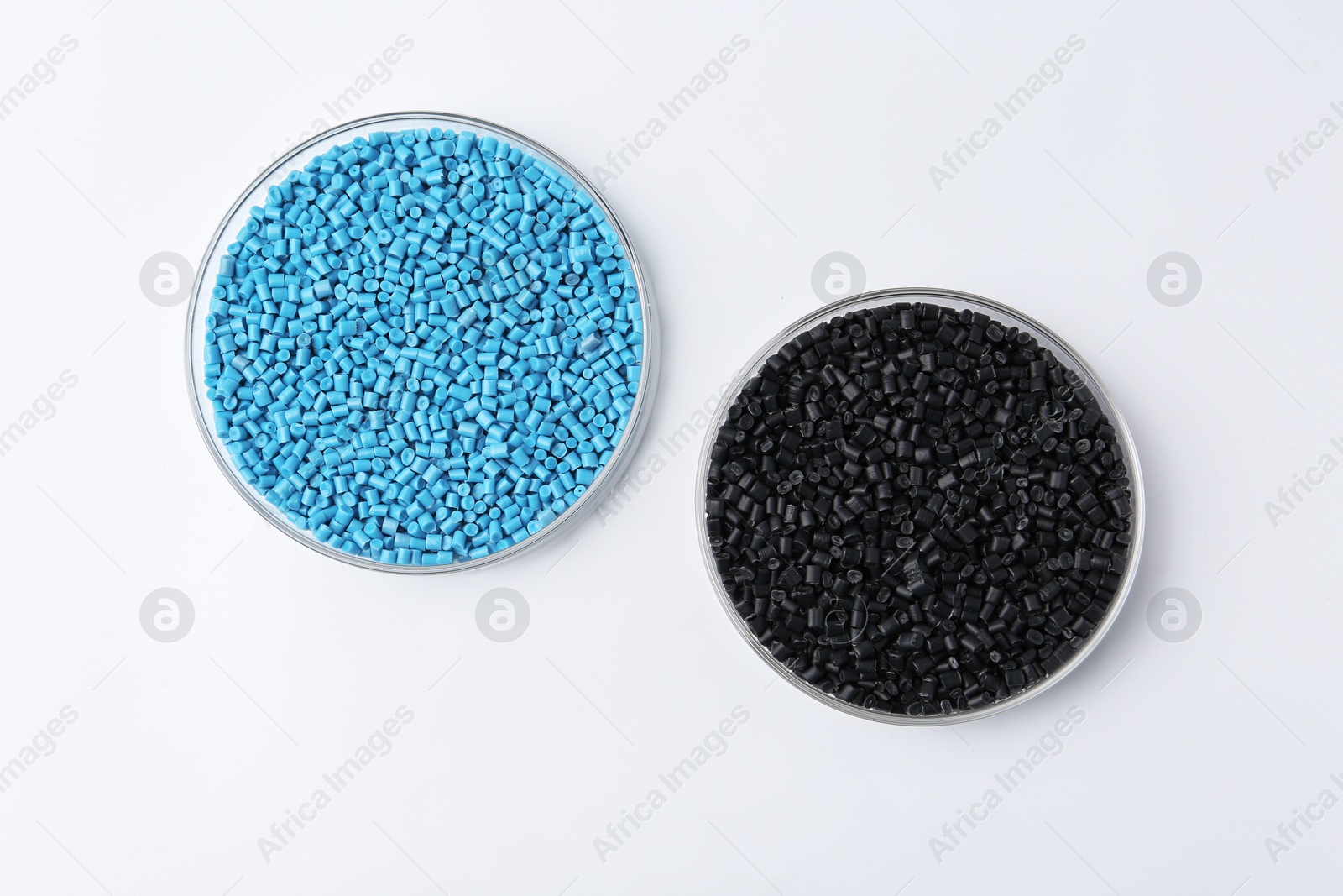 Photo of Colorful plastic granules in petri dishes on white background, flat lay