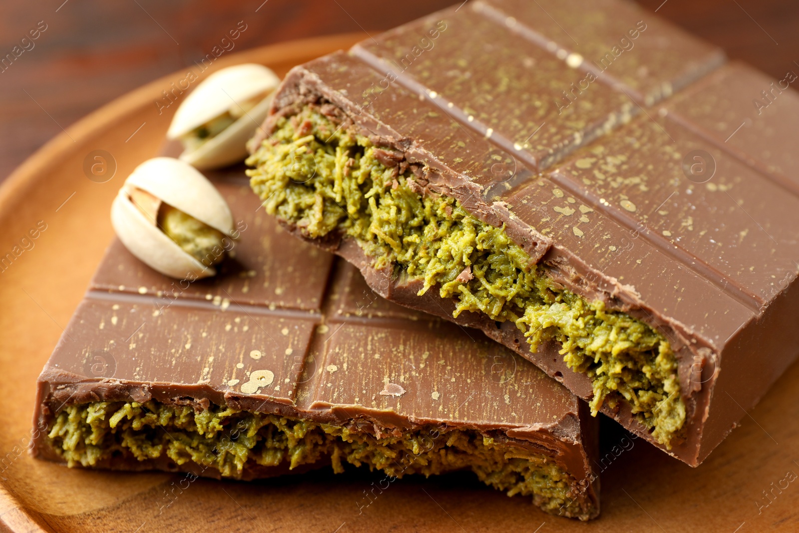 Photo of Pieces of tasty Dubai chocolate with pistachios and knafeh on wooden table, closeup