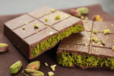 Photo of Pieces of tasty Dubai chocolate bar with pistachios and knafeh on table, closeup