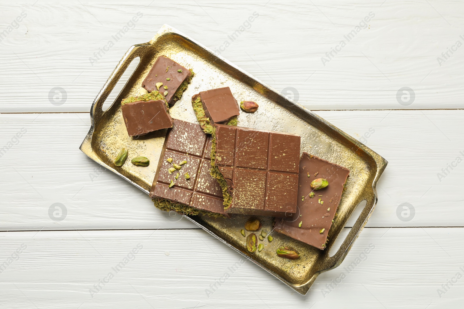 Photo of Pieces of Dubai chocolate bars with pistachios and knafeh on white wooden table, top view