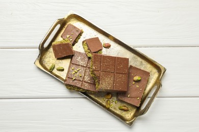 Photo of Pieces of Dubai chocolate bars with pistachios and knafeh on white wooden table, top view