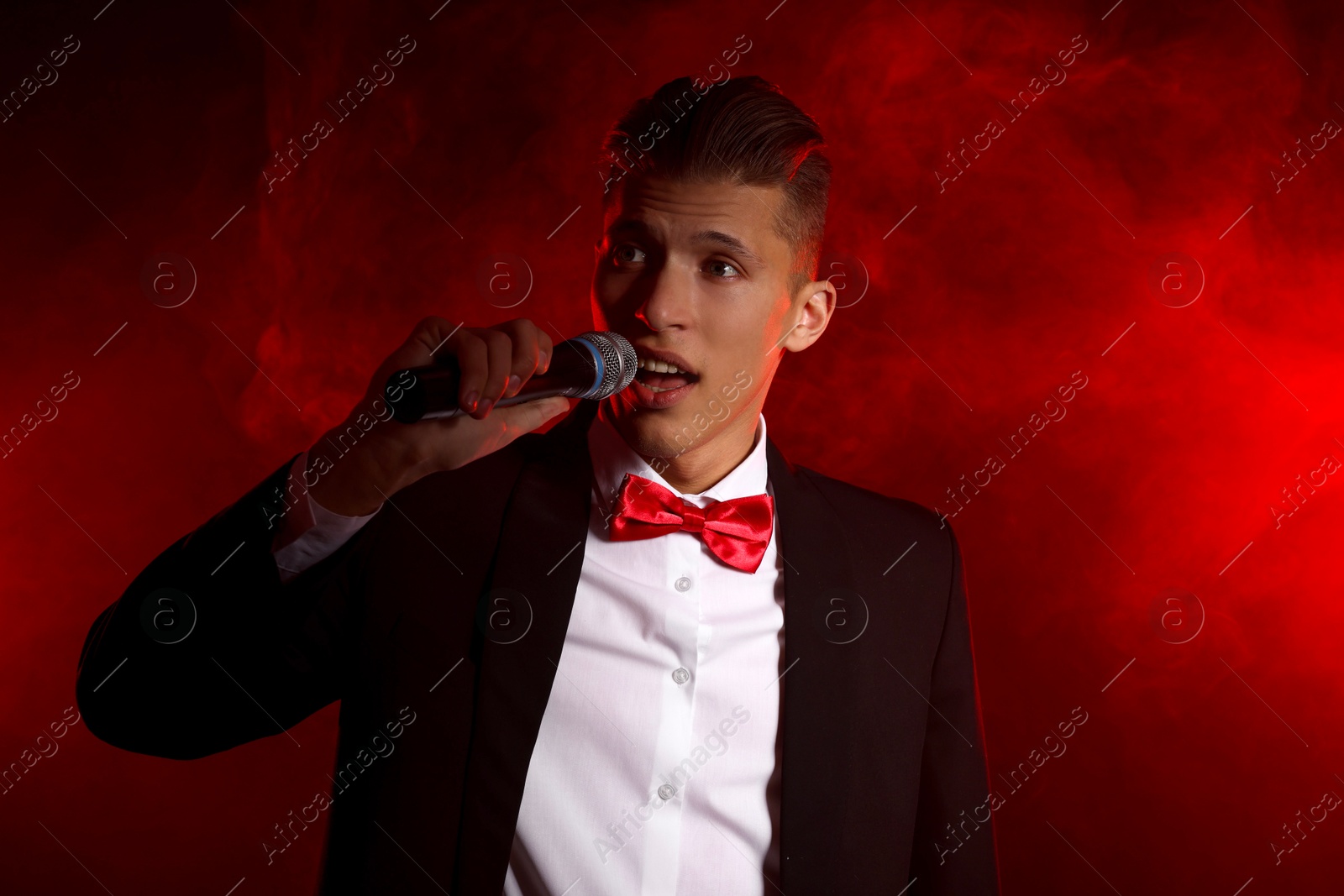 Photo of Talented singer performing on red background with smoke