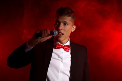 Photo of Talented singer performing on red background with smoke