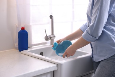 Photo of Woman washing dishes in kitchen sink, closeup