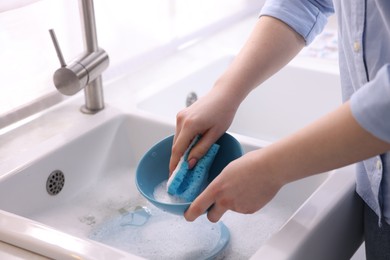 Photo of Woman washing dishes in kitchen sink, closeup