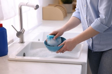 Photo of Woman washing dishes in kitchen sink, closeup