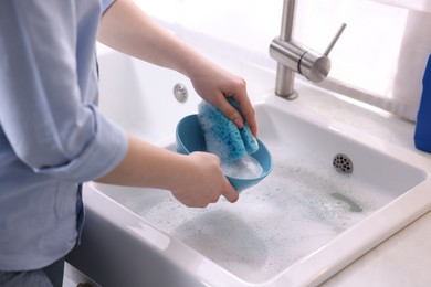 Photo of Woman washing dishes in kitchen sink, closeup