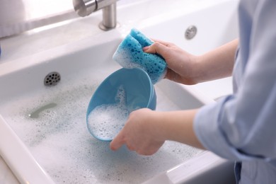 Photo of Woman washing dishes in kitchen sink, closeup