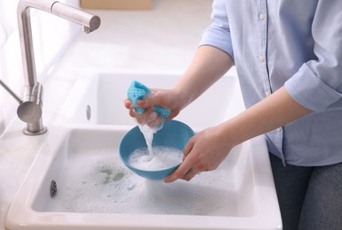 Photo of Woman washing dishes in kitchen sink, closeup