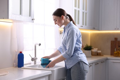 Photo of Happy woman washing dishes in kitchen sink