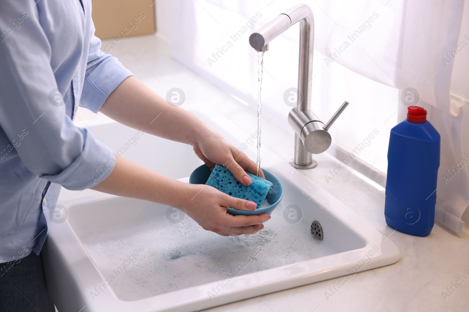 Photo of Woman washing dishes in kitchen sink, closeup