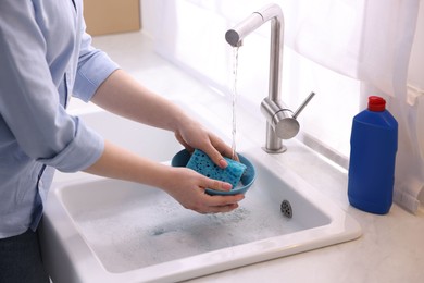 Photo of Woman washing dishes in kitchen sink, closeup