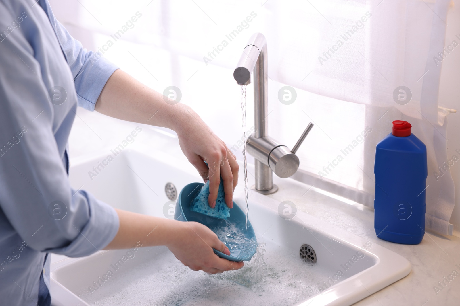 Photo of Woman washing dishes in kitchen sink, closeup