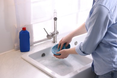 Photo of Woman washing dishes in kitchen sink, closeup