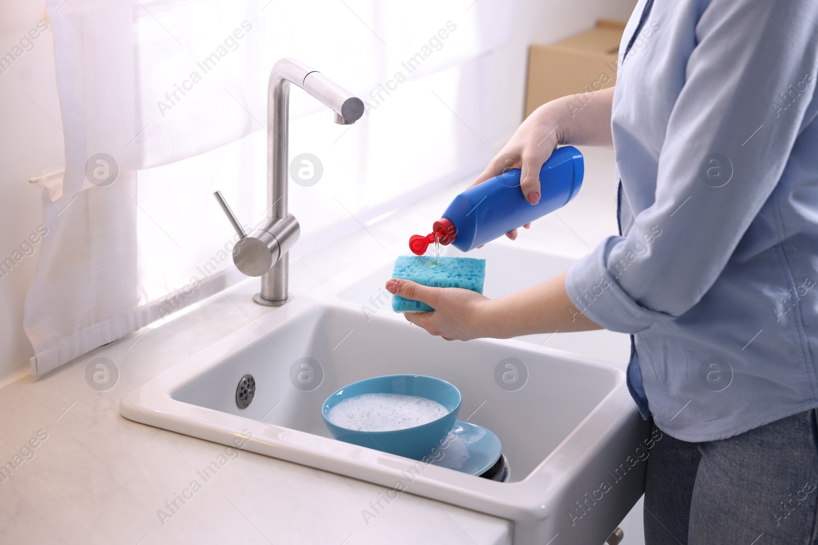 Photo of Woman washing dishes in kitchen sink, closeup