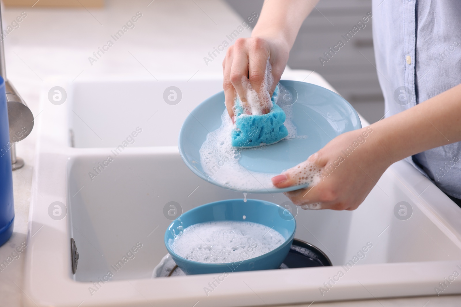 Photo of Woman washing dishes in kitchen sink, closeup