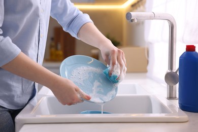 Photo of Woman washing dishes in kitchen sink, closeup