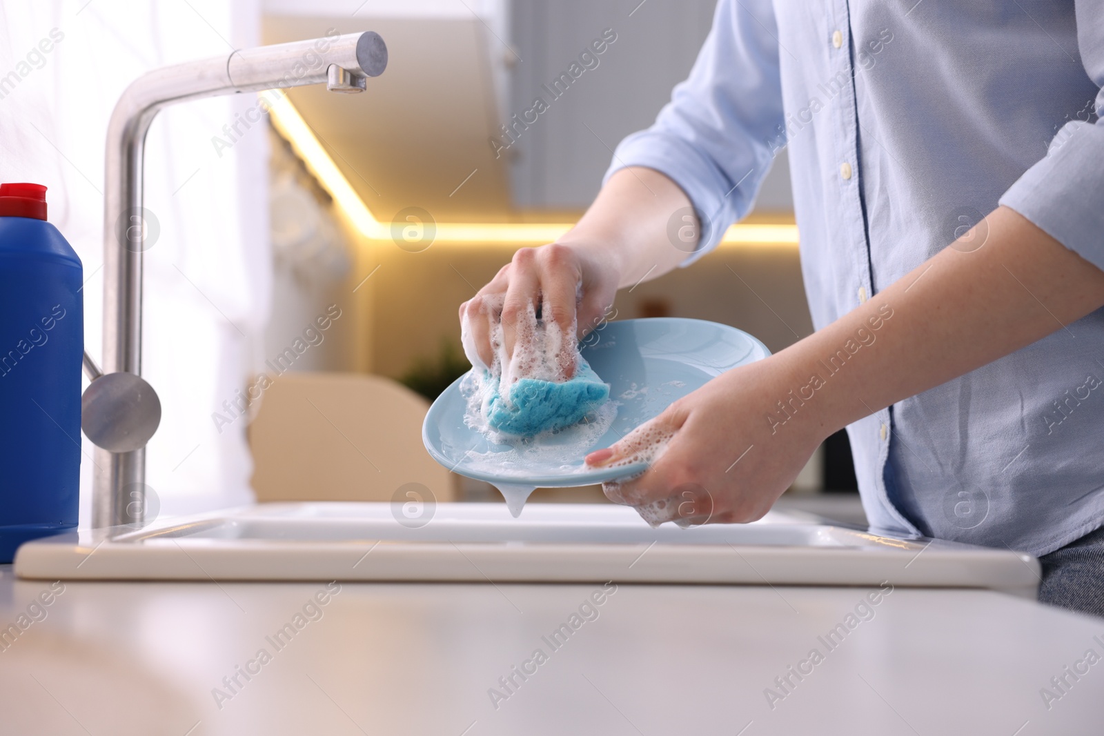 Photo of Woman washing dishes in kitchen sink, closeup