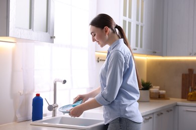 Photo of Smiling woman washing dishes in kitchen sink