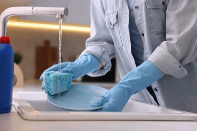 Photo of Woman washing dishes in kitchen sink, closeup