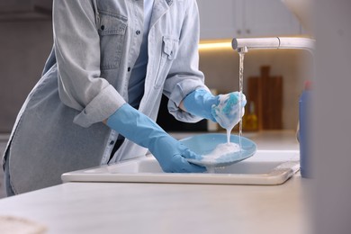 Photo of Woman washing dishes in kitchen sink, closeup