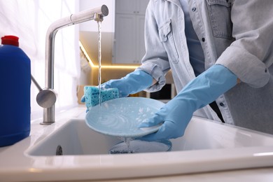 Photo of Woman washing dishes in kitchen sink, closeup