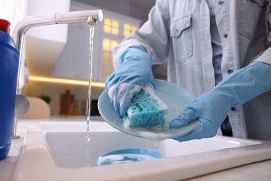 Photo of Woman washing dishes in kitchen sink, closeup