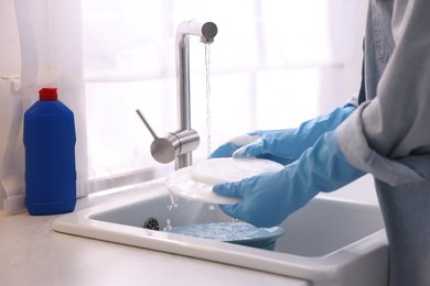 Photo of Woman washing dishes in kitchen sink, closeup