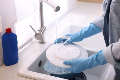 Photo of Woman washing dishes in kitchen sink, closeup