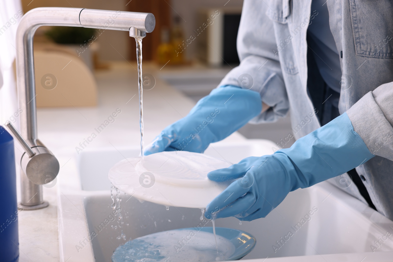 Photo of Woman washing dishes in kitchen sink, closeup