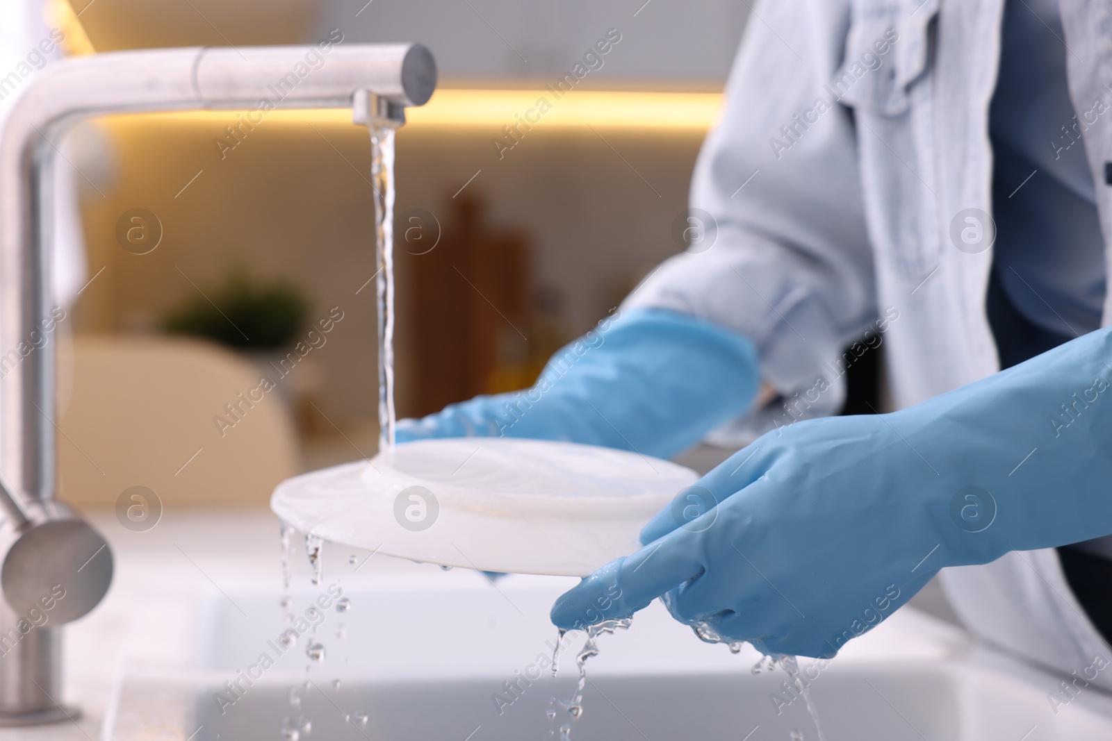 Photo of Woman washing dishes in kitchen sink, closeup