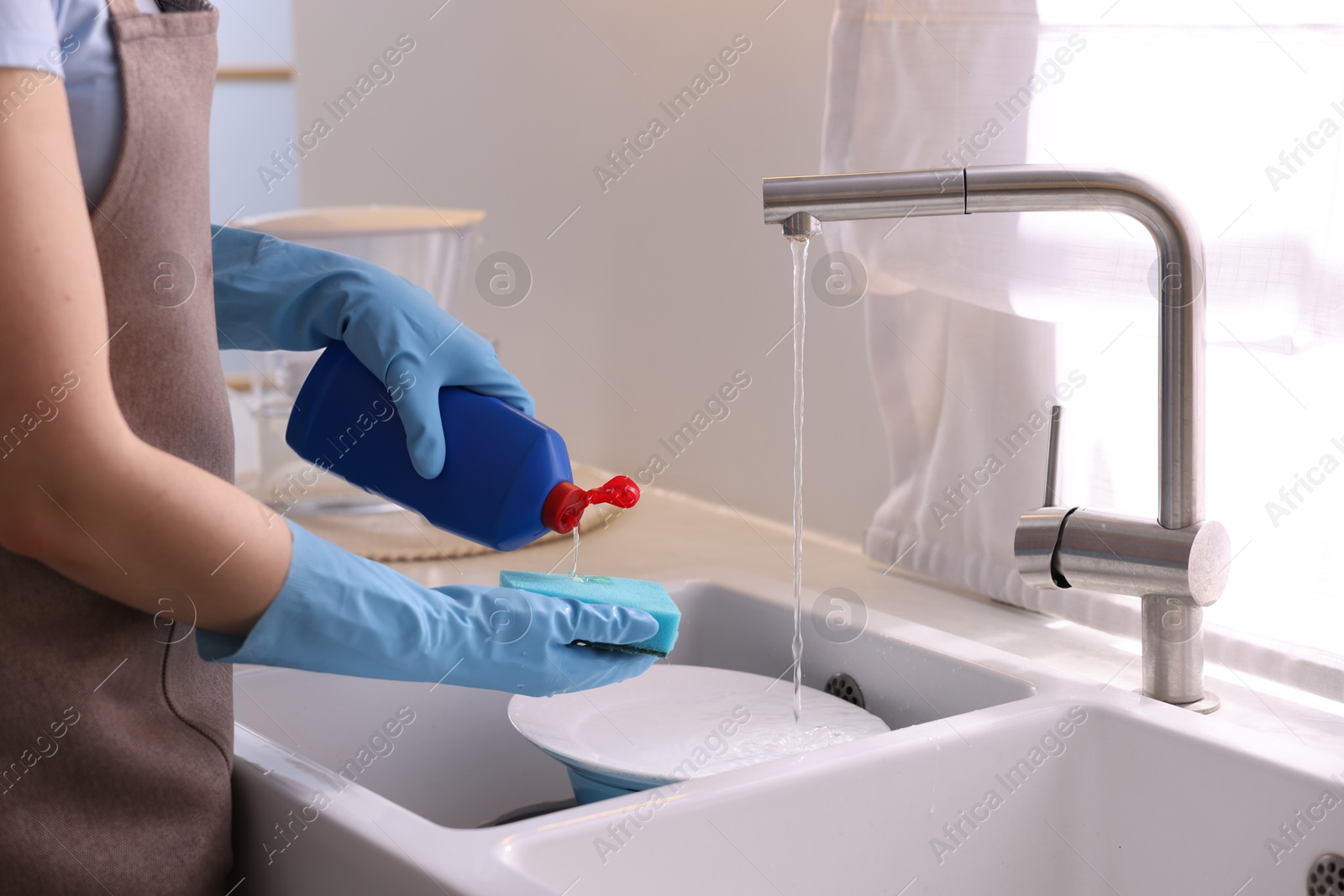 Photo of Woman washing dishes in kitchen sink, closeup