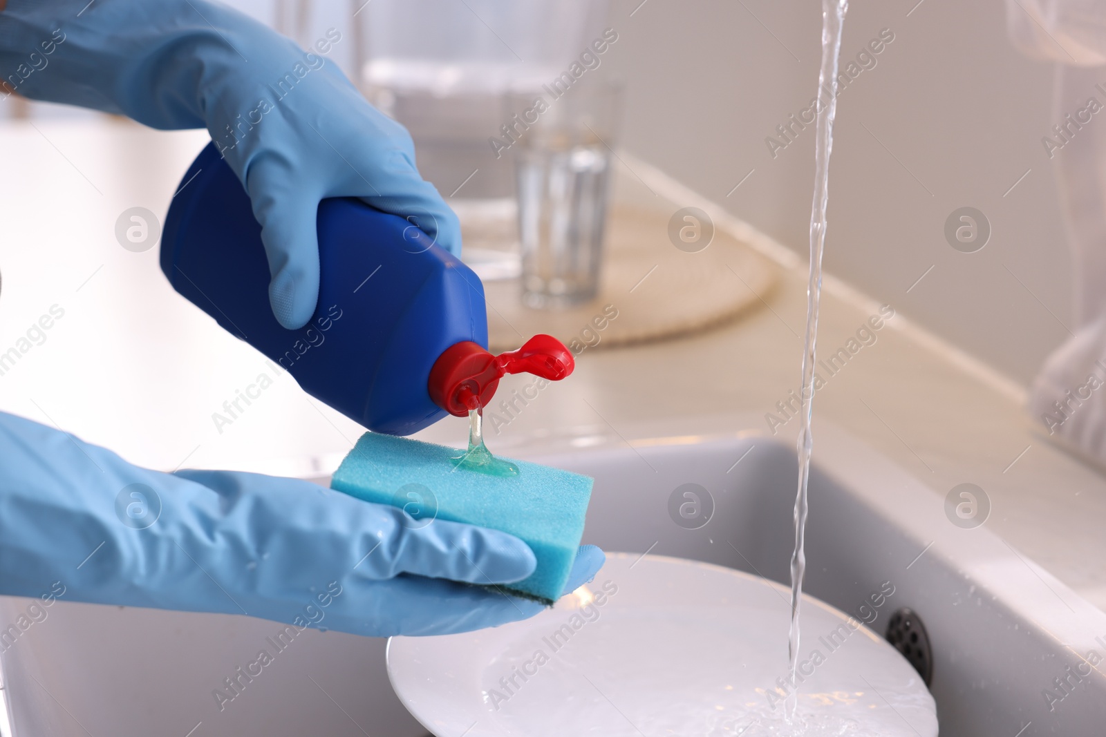 Photo of Woman washing dishes in kitchen sink, closeup