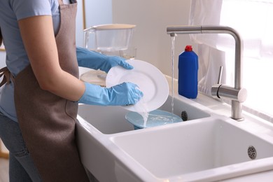 Photo of Woman washing dishes in kitchen sink, closeup